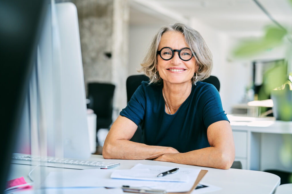Portrait of confident mature businesswoman. Smiling female professional is working in creative office. She is wearing eyeglasses.