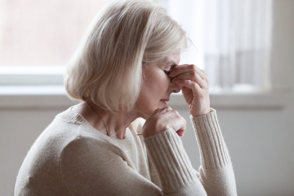 Fatigued upset older woman massaging nose bridge feeling eye strain